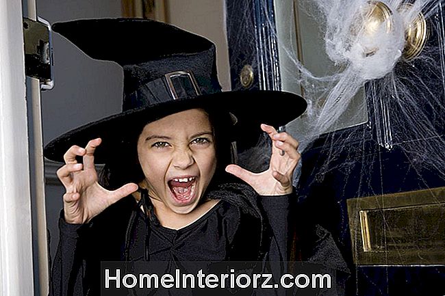 Jong meisje bij de voordeur, verkleed als een heks voor Halloween