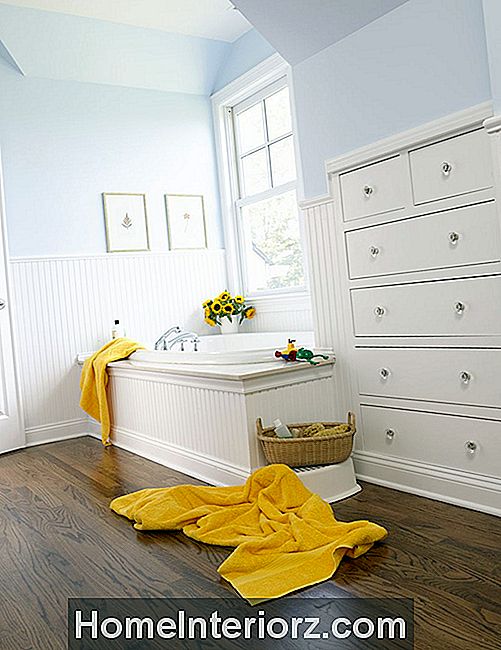 Valkoinen kylpyhuone, jossa on sisäänrakennetut laatikot ja keltaiset pyyhkeet