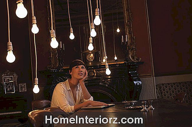 Kvinna som sitter vid bordet stirrar på hängande ljus.