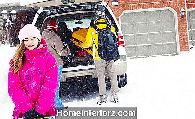 Flicka står framför packad bil på vintern