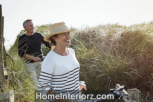 Coppie mature che camminano biciclette lungo spiaggia beach grass