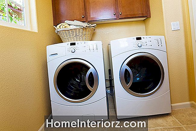 Vit modern tvättmaskin och torktumlare i hemmets tvättstuga.