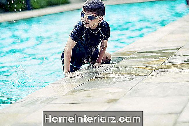Noor poiss, kellel on kaitseprillid basseinis ujumas